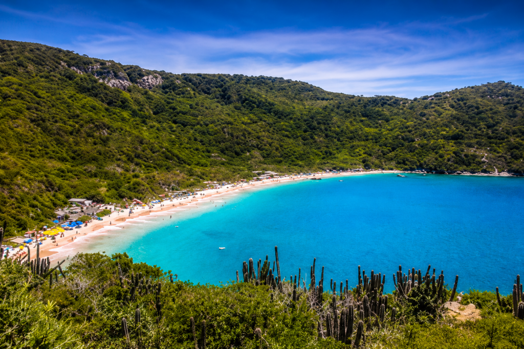 Vista panorâmica da Praia do Forno em Arraial do Cabo, Rio de Janeiro, com águas cristalinas azul-turquesa, areia branca e vegetação preservada.